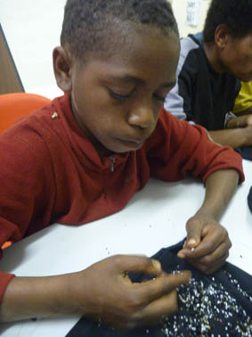 Taxi Boys learning to make necklaces as part of the youth development program.